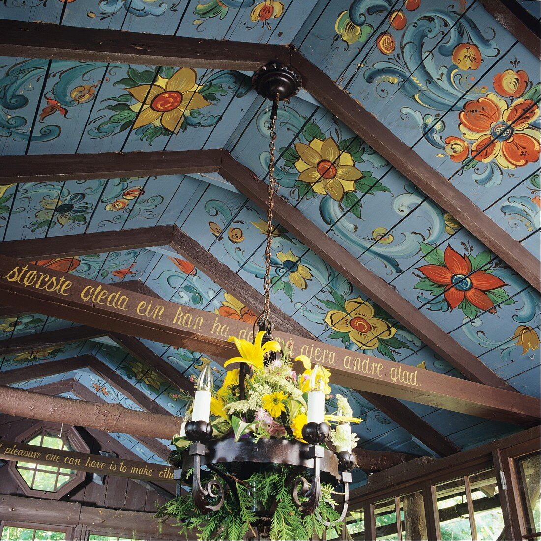 Wooden ceiling painted with Norwegian floral motifs and chandelier decorated with fresh flowers