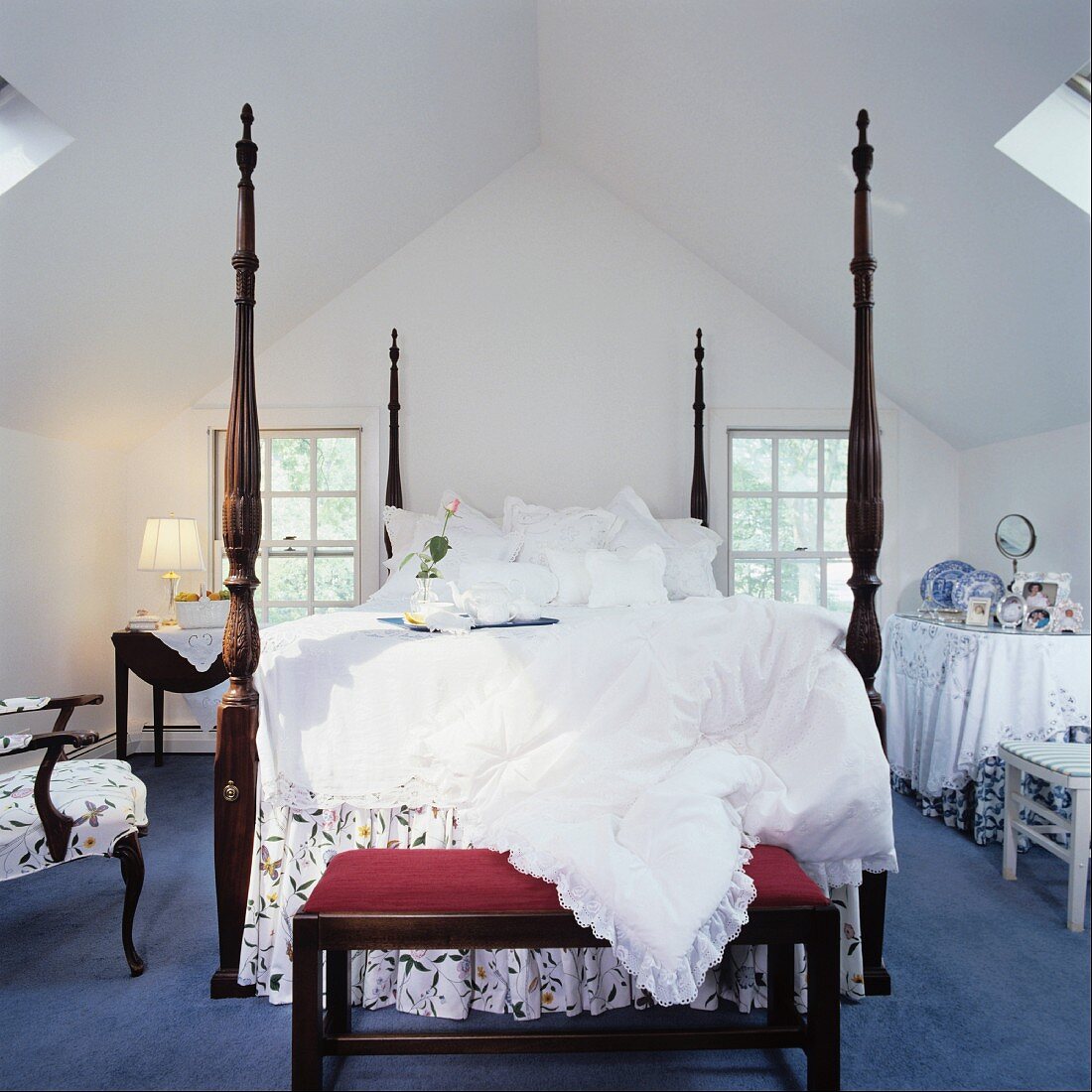 Herrschaftliches Bett mit hohen Bettpfosten und einer gepolsterten Sitzbank unter dem Dach