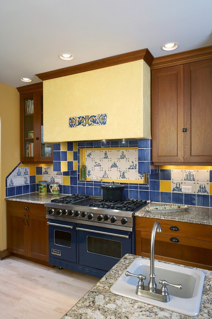 Modern fitted kitchen with wooden cupboards and patterns of yellow and blue wall tiles