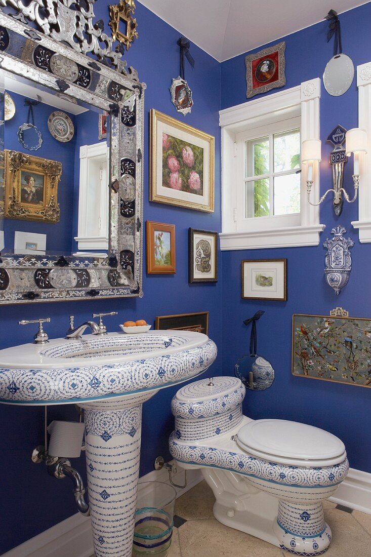 Originelles Badezimmer mit handbemaltem Standwaschbecken, handbemalter Toilette und venezianischem Spiegel