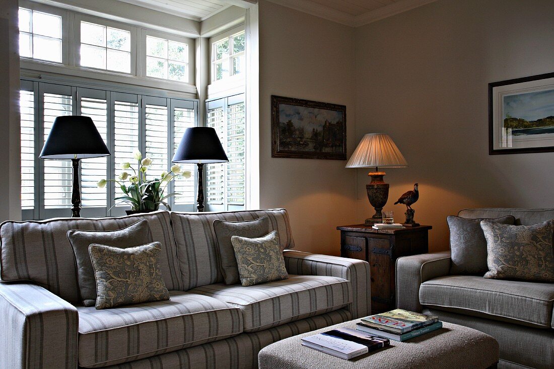Sofa with striped upholstery in front of bay window in rustic ambiance