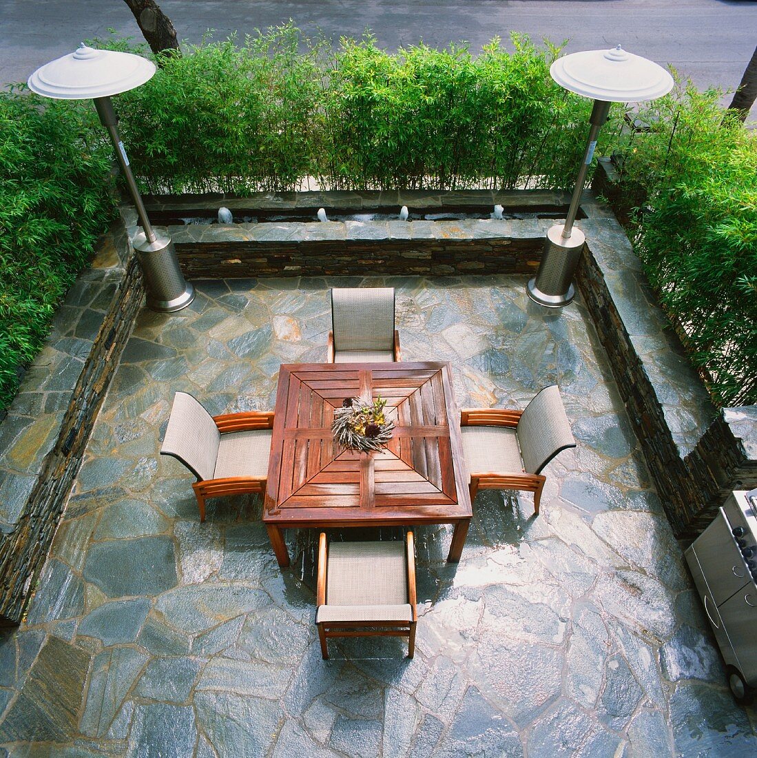 Blick auf Terrasse mit Natursteinbelag und Outdoor Tisch mit Stuhlgarnitur