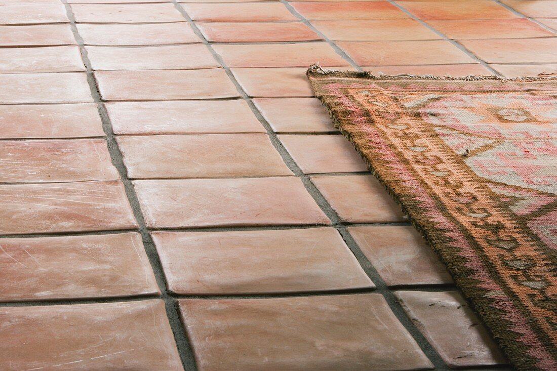 Folkloristischer Teppich auf Terrakottaboden