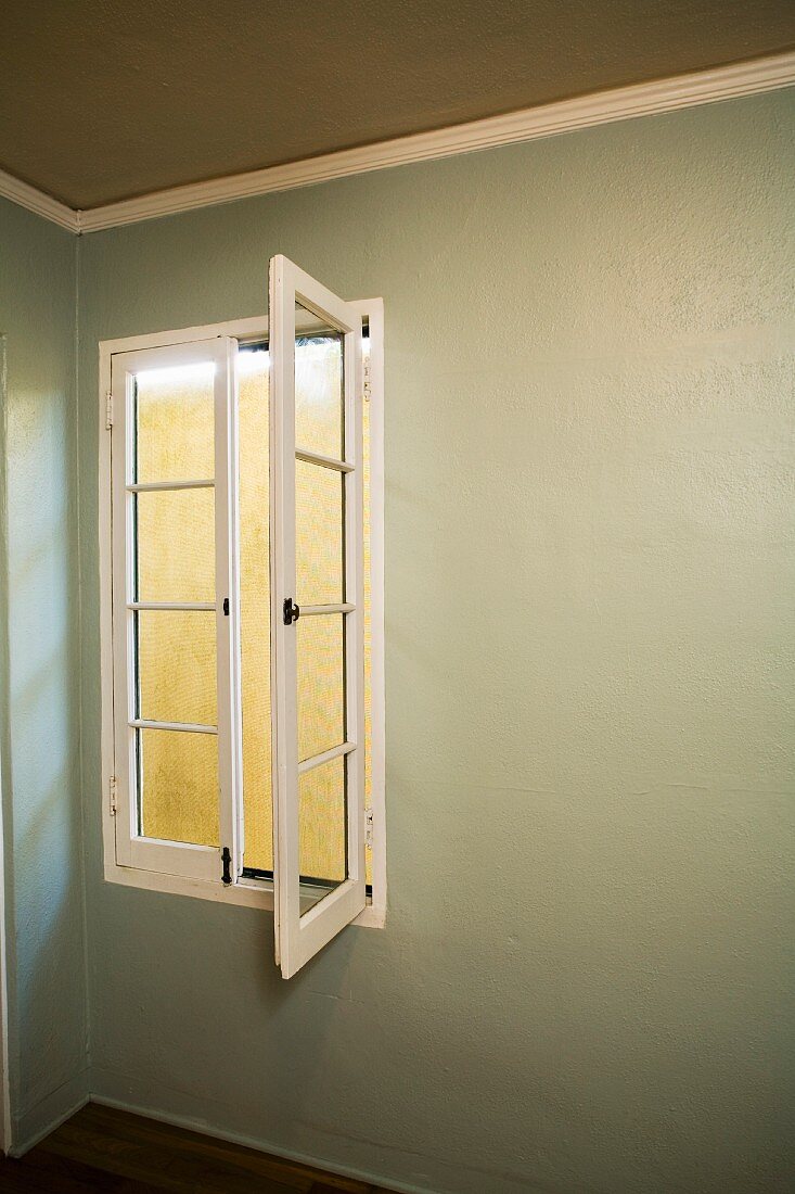 Offenstehendes Sprossenfenster in olivfarben getöntem Raum