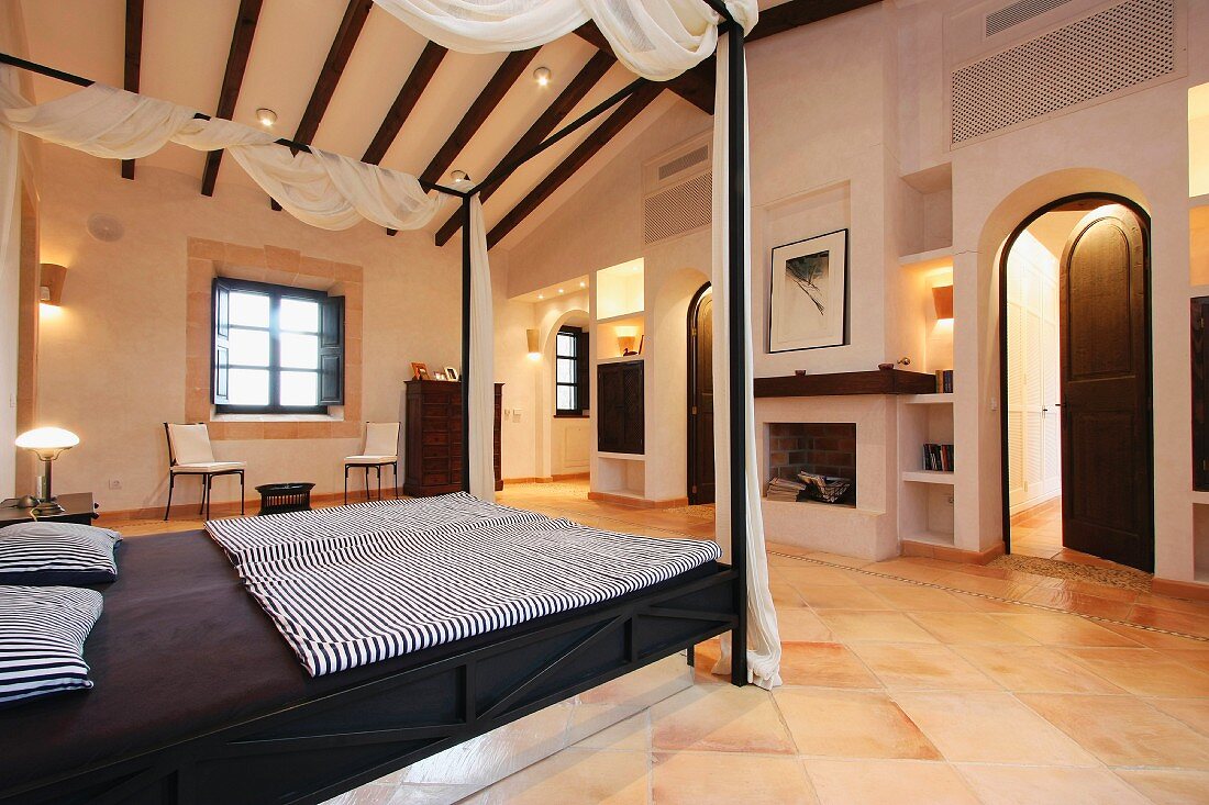 Elegantes Himmelbett mit Vorhang in Schlafzimmer eines mediterranen Landhauses