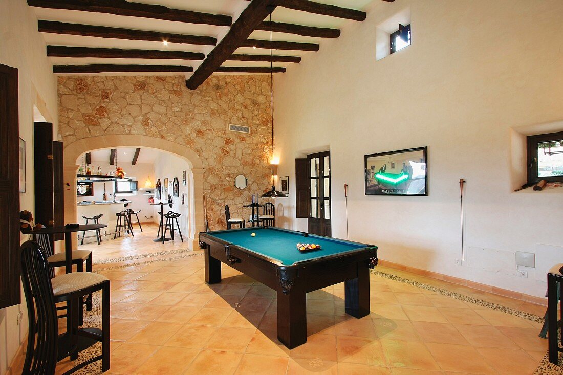 Gesellschaftszimmer mit Billardtisch und breitem Durchgang mit Blick auf Bar in mediterranem Landhaus
