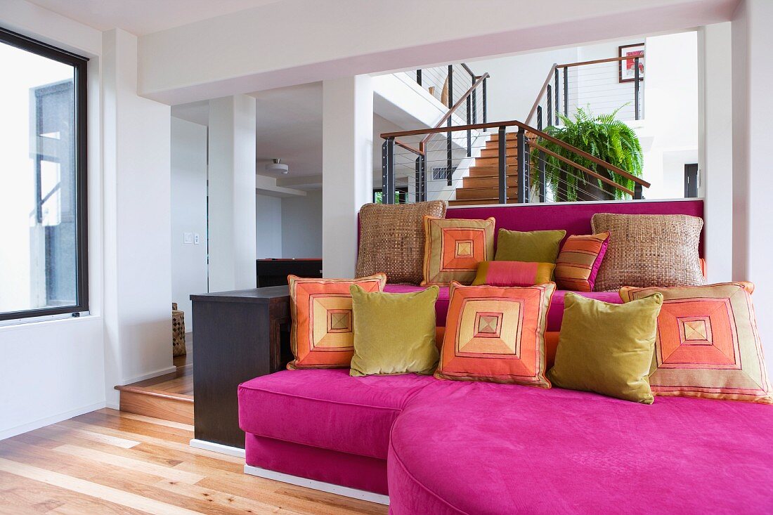 Pinkfarbene Sofa mit bunten Dekokissen
