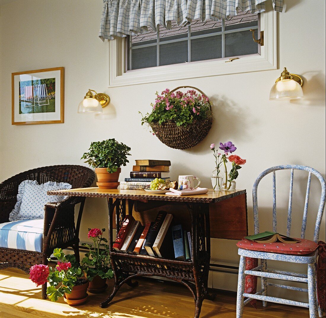 Books and flowers on table, wicker armchair and chair on veranda