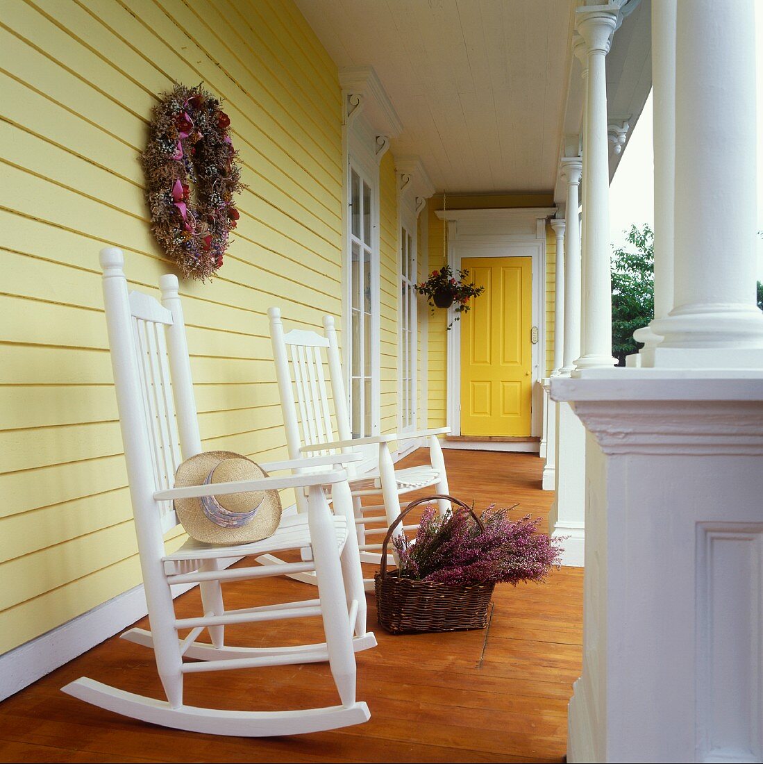 Two rocking chairs and a basket of heather on a yellow-painted veranda