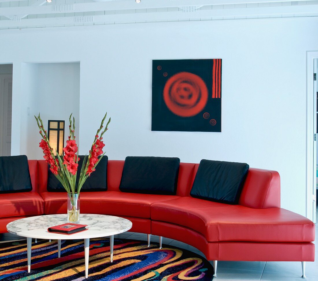 Halbrundes Designer Sofa mit buntem Teppich und moderner Kunst im Hintergrund