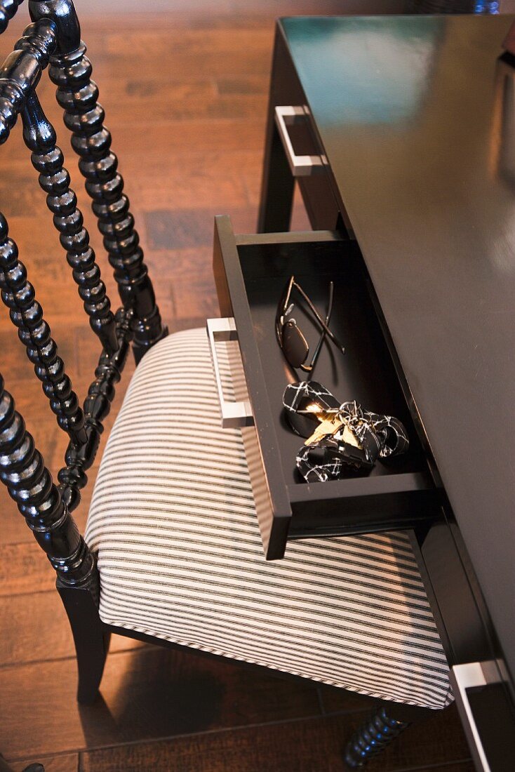 Offene Schreibtischschublade und klassischer Polsterstuhl aus schwarzem, gedrechseltem Holz