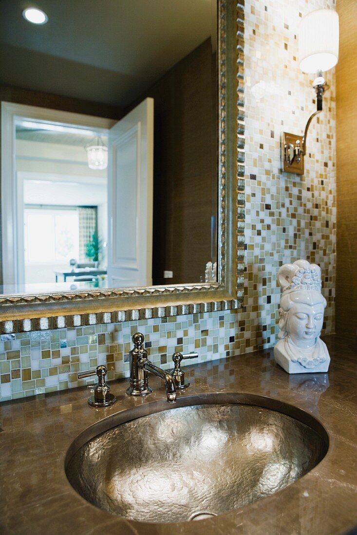 Waschtisch mit handgehämmertem Unterbaubecken vor Spiegelwand mit Mosaikfliesen