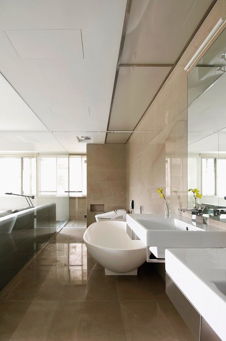 Glastrennscheibe zwischen Schlafzimmer und Designerbad mit glänzenden, hellbraunen Boden- und Wandfliesen