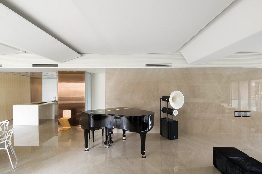 Schwarzer Klavierflügel neben Retro Lautsprecher im loftartigen Wohnraum mit glänzende Wand- und Bodenfliesen in Hellbraun