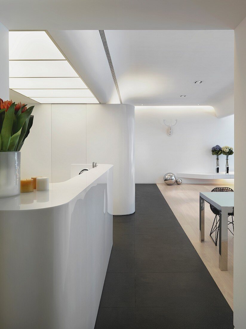weiße glänzende Theke unter Milchglasdecke in minimalistisch eingerichtetem Wohnraum