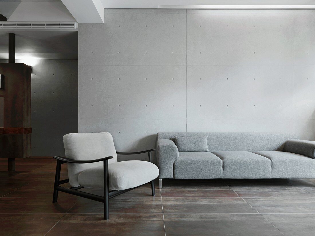Sessel im Fiftiesstil neben modernem grauen Polstersofa im schlichten Wohnraum