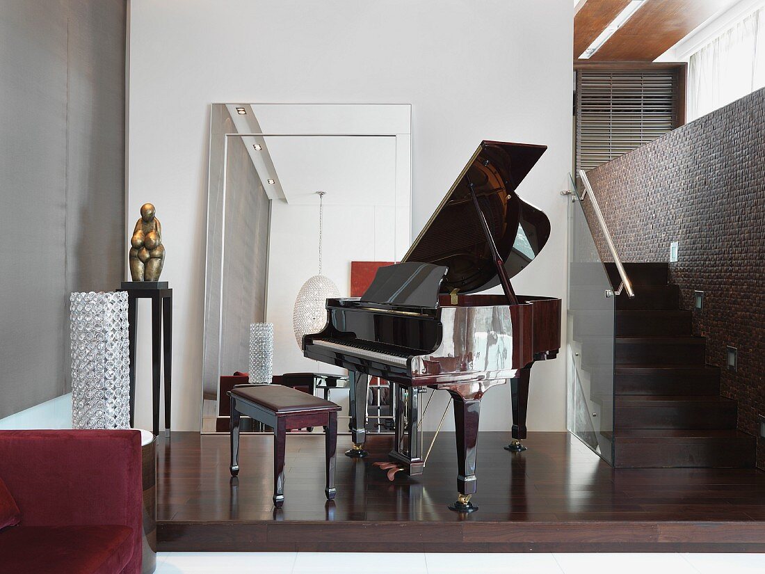 Klavierflügel und Standspiegel auf Podest mit Treppe aus dunklem Holz