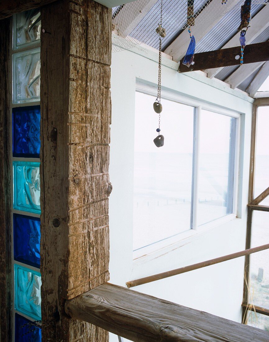 Balcony supports of wooden beams with integrated strips of blue glass bricks