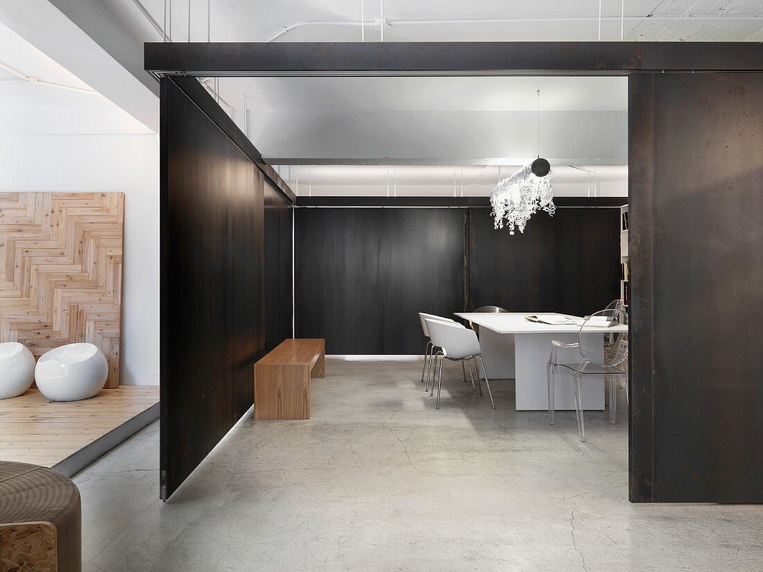 Esszimmer mit weißem Holztisch und Schalenstühlen in offenem Wohnraum mit dunkelbraunen, verschiebbaren Trennwänden