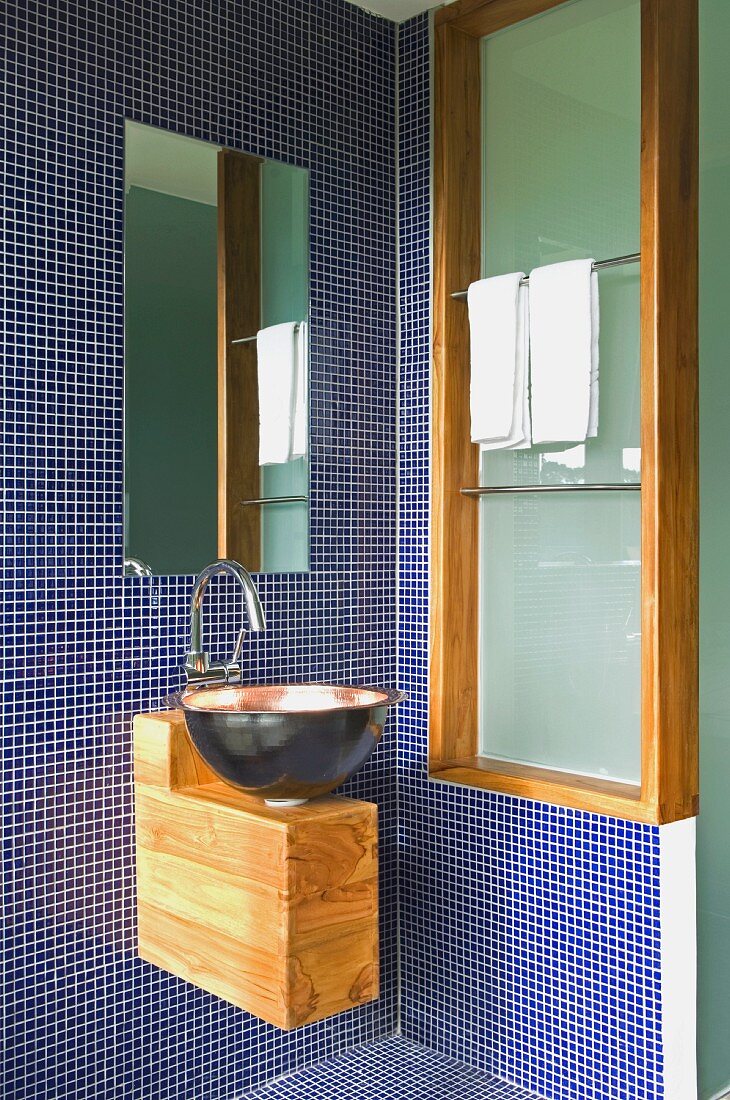 Badezimmerecke mit blauen Mosaikfliesen und einer Waschschüssel aus Kupfer