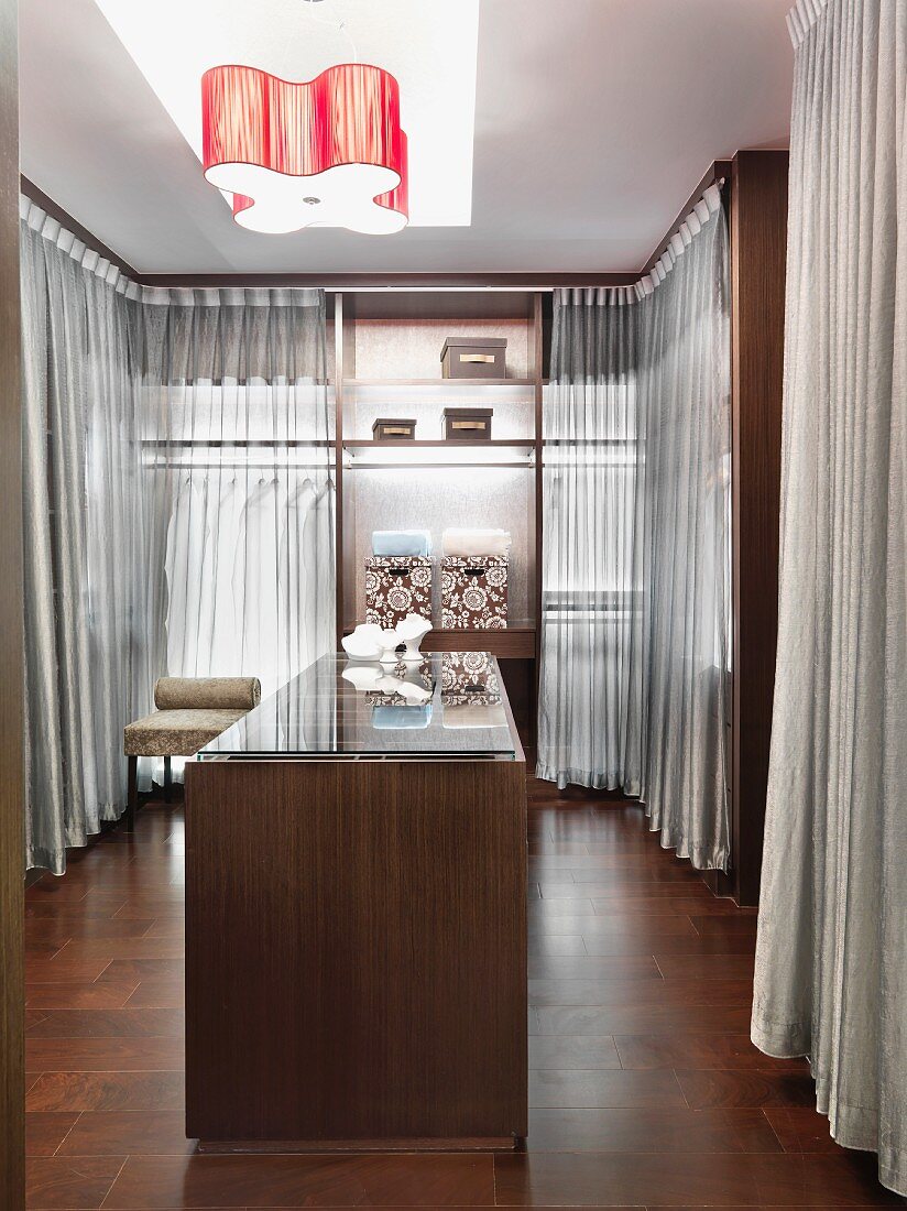 Großräumiger Ankleideraum mit transparenten Vorhängen und einer Schmuckvitrine in der Mitte des Raums