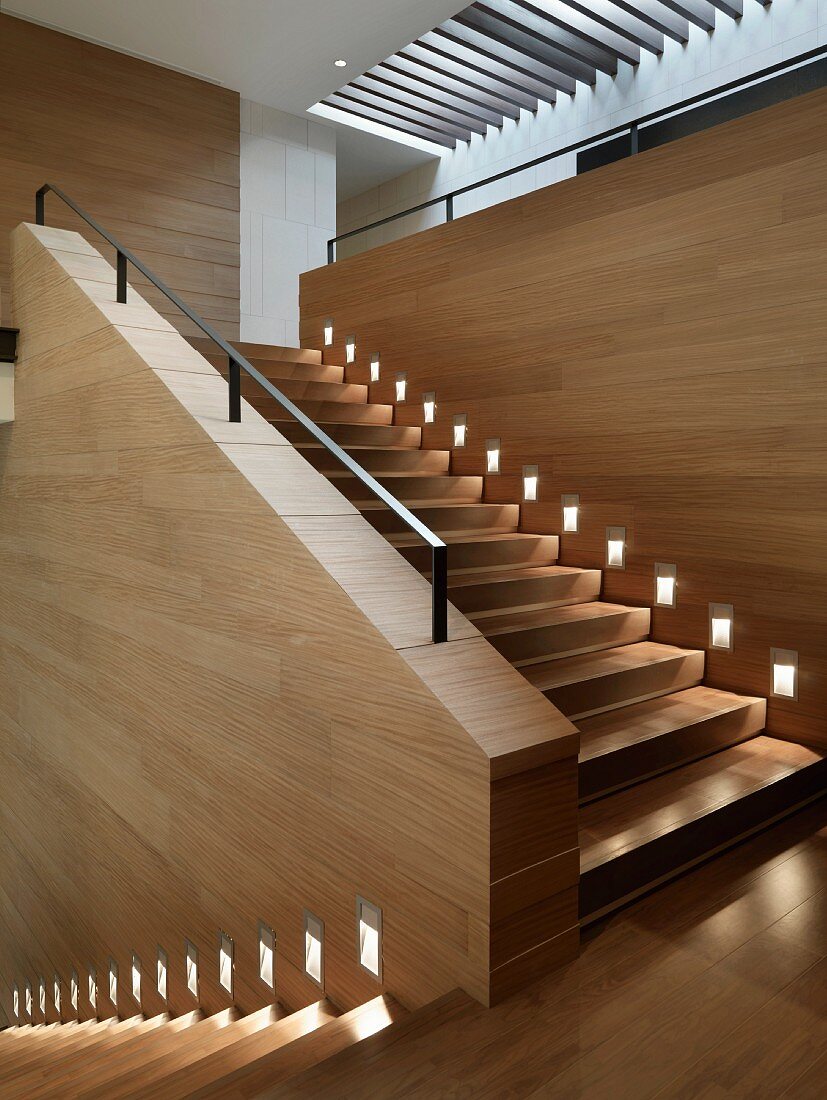 Elegantes, modernes Treppenhaus mit heller Holzverkleidung und einer durchgehenden Treppenbeleuchtung