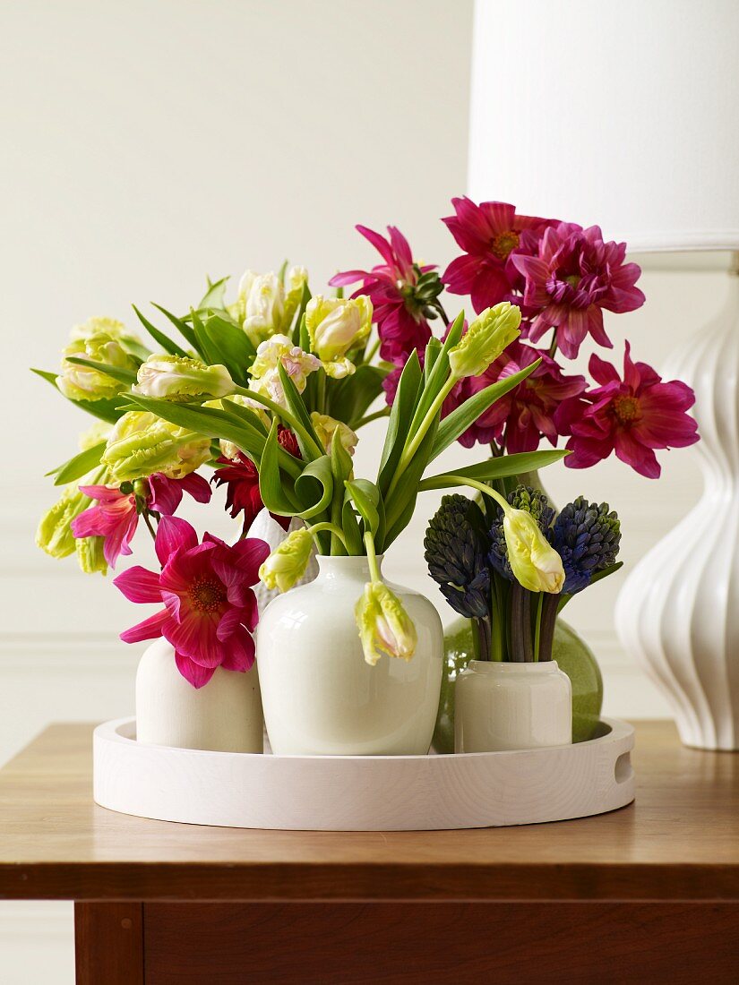 White Vases Arranged on a Tray Filled with Spring Flowers; Lamp