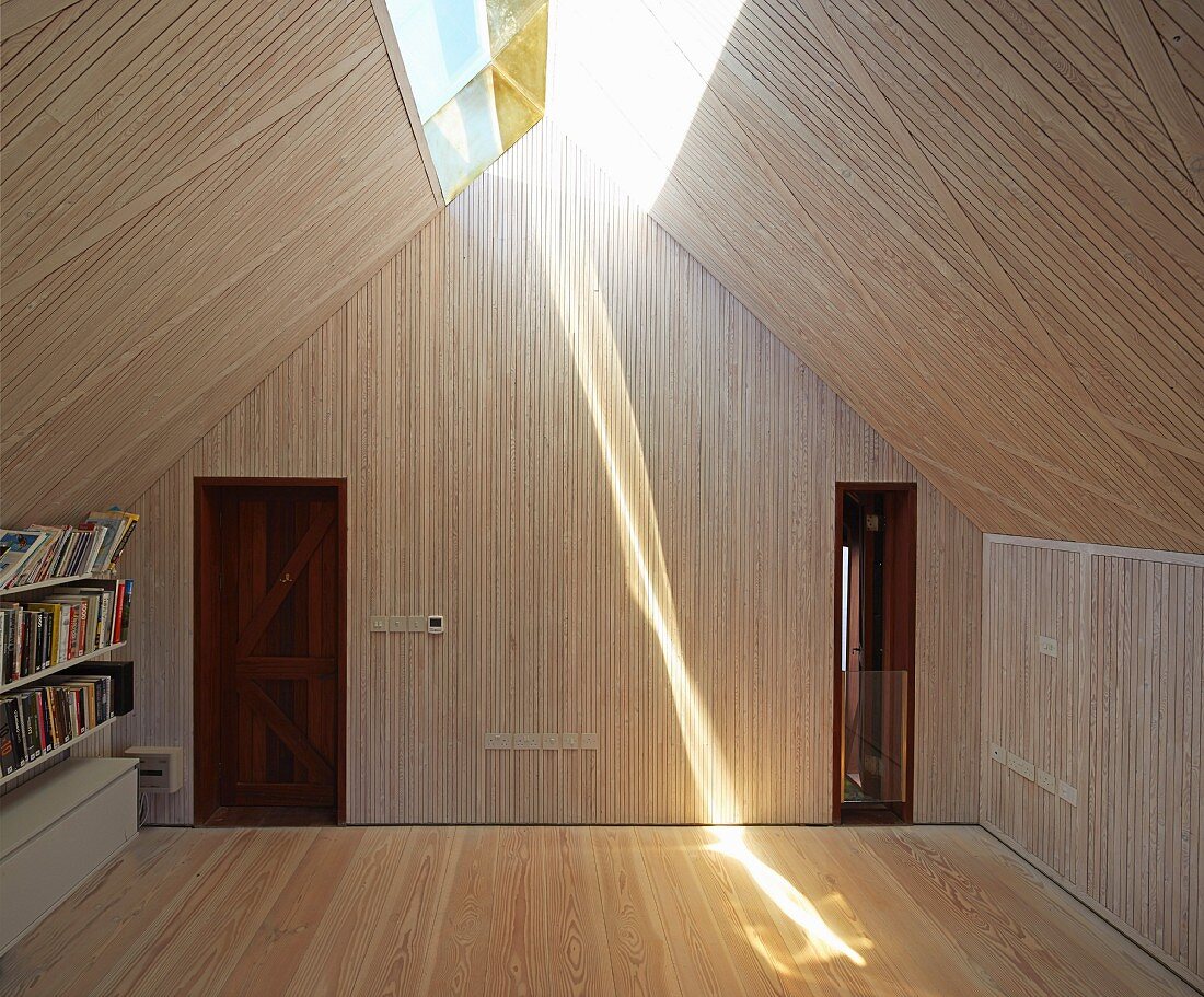 Raum mit Holzverkleidung und Oberlichtband in Dachschräge, strahlende Lichtreflexion auf Dielenboden
