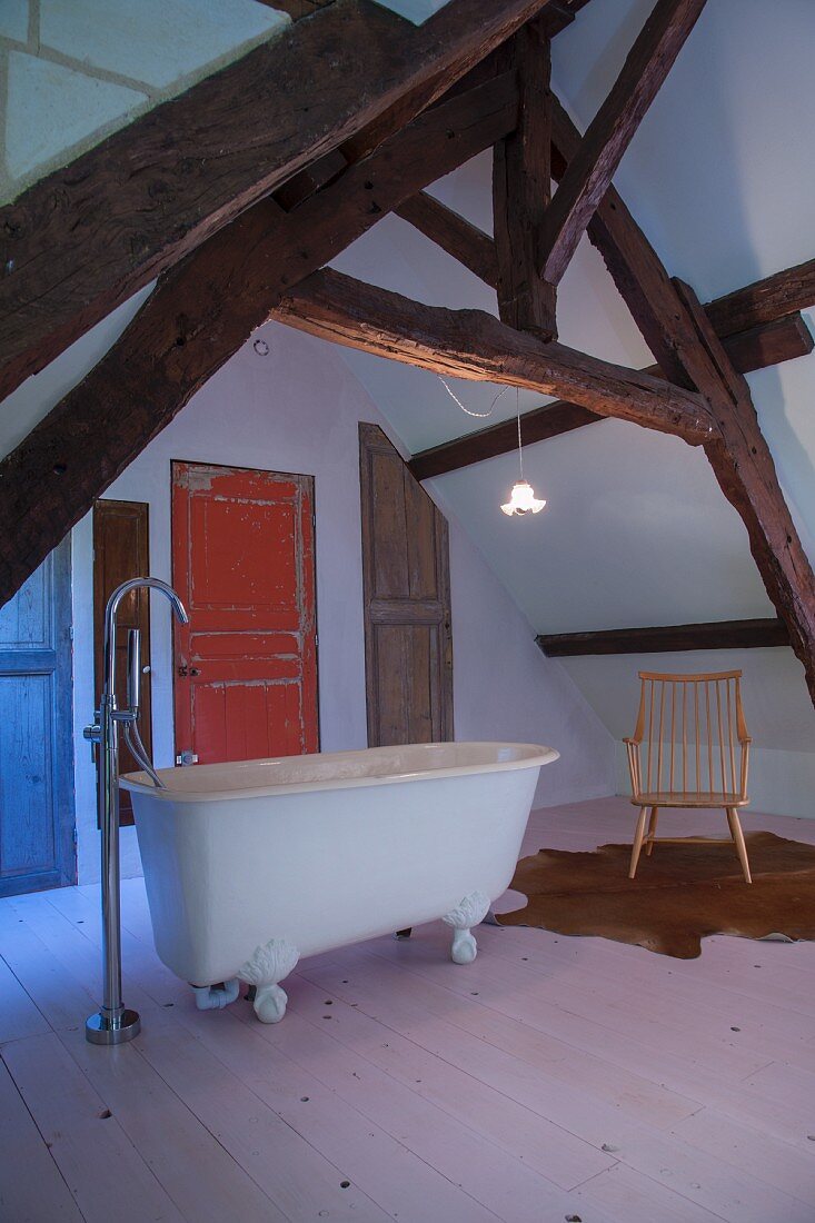 Ausgebautes Dachgeschoss mit freistehender Badewanne, rustikalen Sichtbalken und Vintage-Türblättern