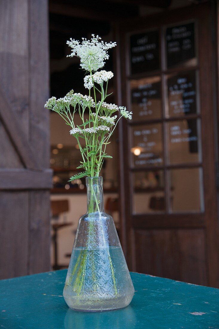 Vintage Glasvase mit weiß blühenden Wiesenblumen