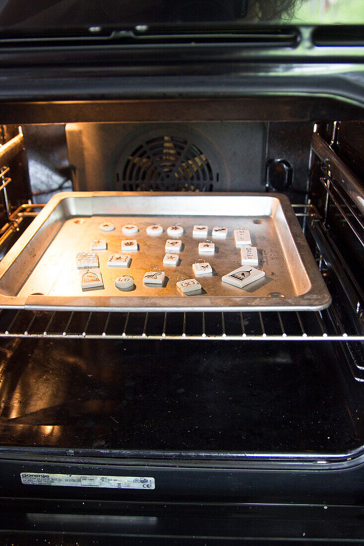 Fired polymer clay gift tags on baking tray in oven