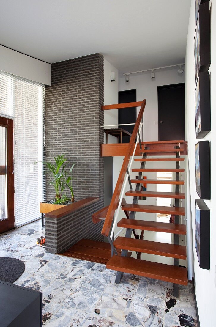 Treppe mit Holztrittstufen auf Metall Untergestell, im Vordergrund Bodenbelag aus Natursteinplatten in Retro Diele