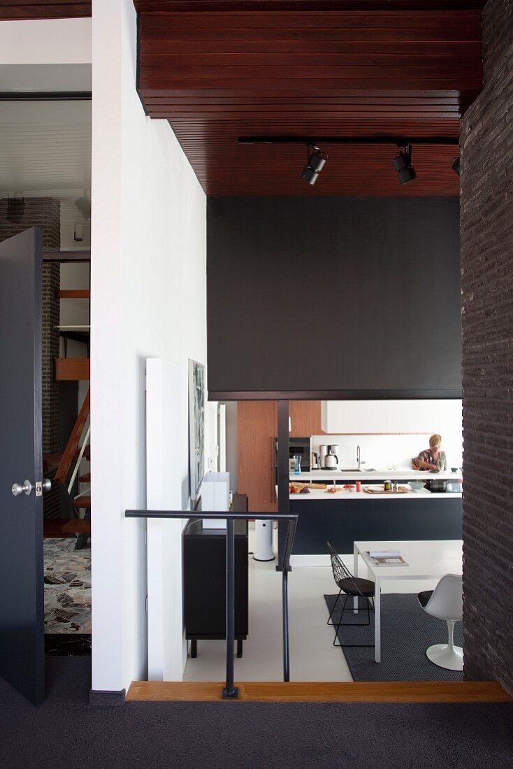 View from foyer into sunken, open-plan kitchen with black and white colour scheme