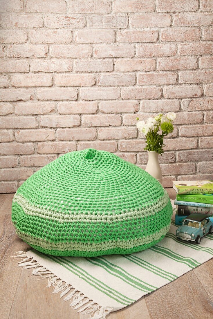 Crocheted green pouffe on green and white rug