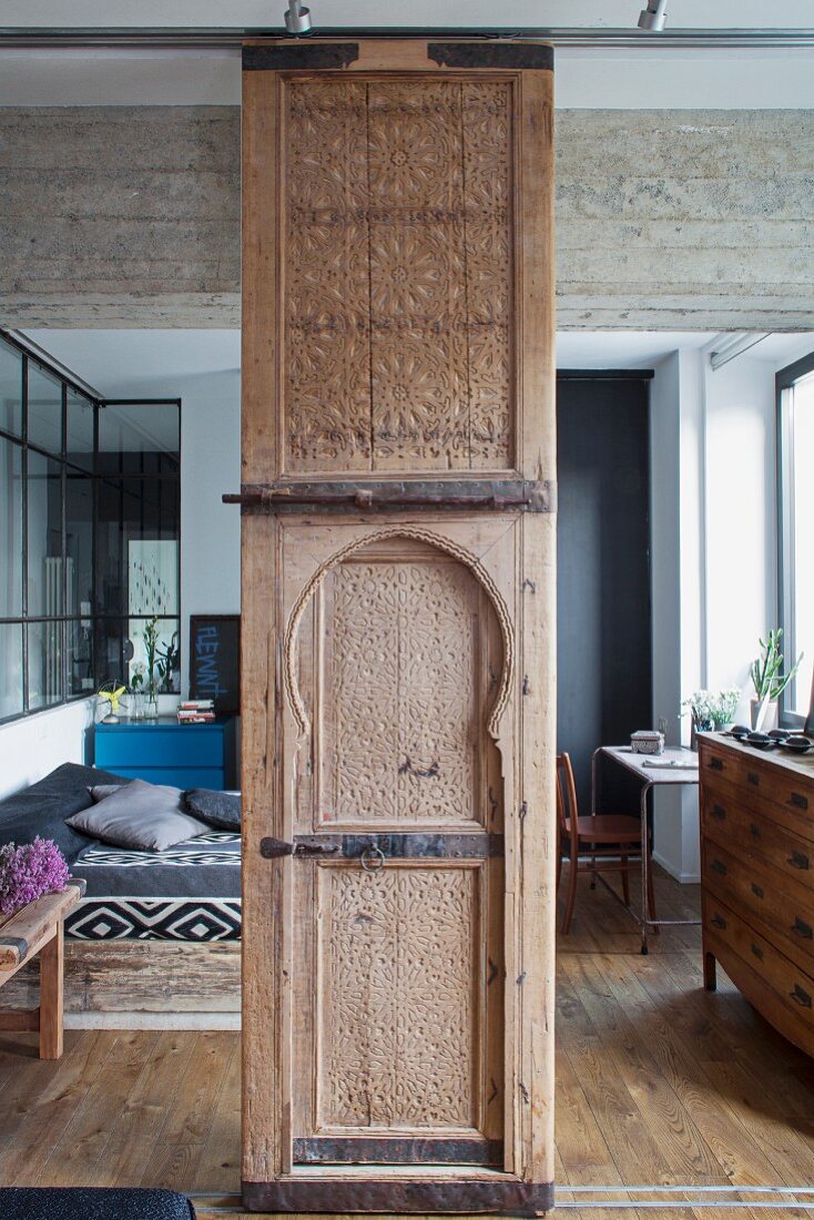 Moroccan handcrafted wooden element as sliding element in front of a bedroom area