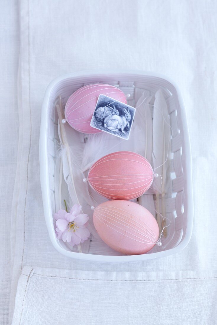 Pink eggs decorated with threads in a dish