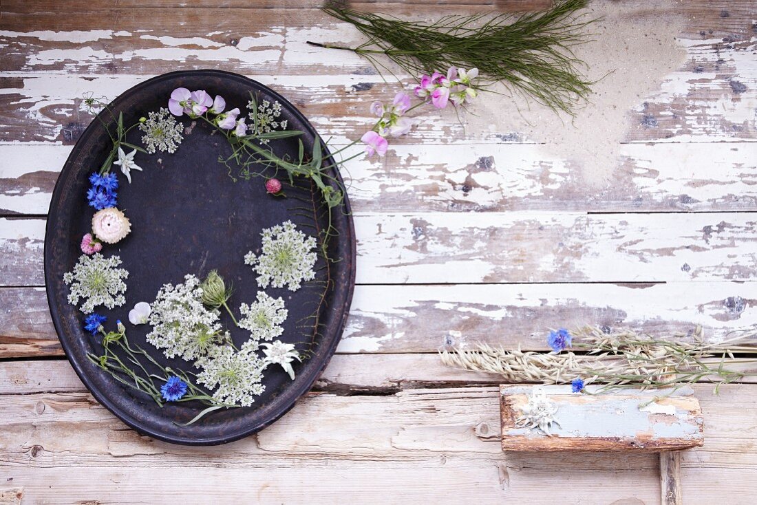 Tablett dekoriert mit Sommerblüten auf Holzuntergrund