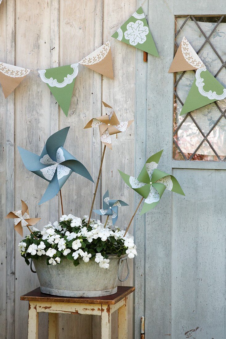 Hand-made windmills in planter and bunting decorating wooden shed