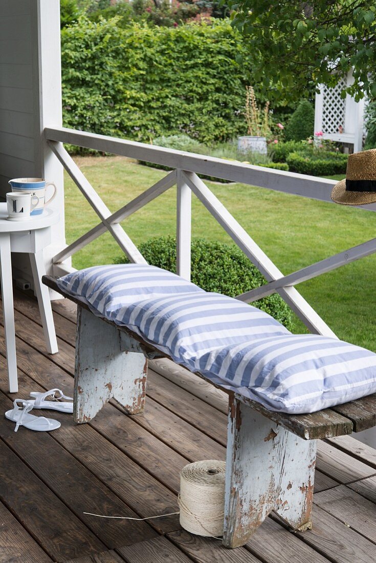 A bench on a terrace with a homemade, striped cushion