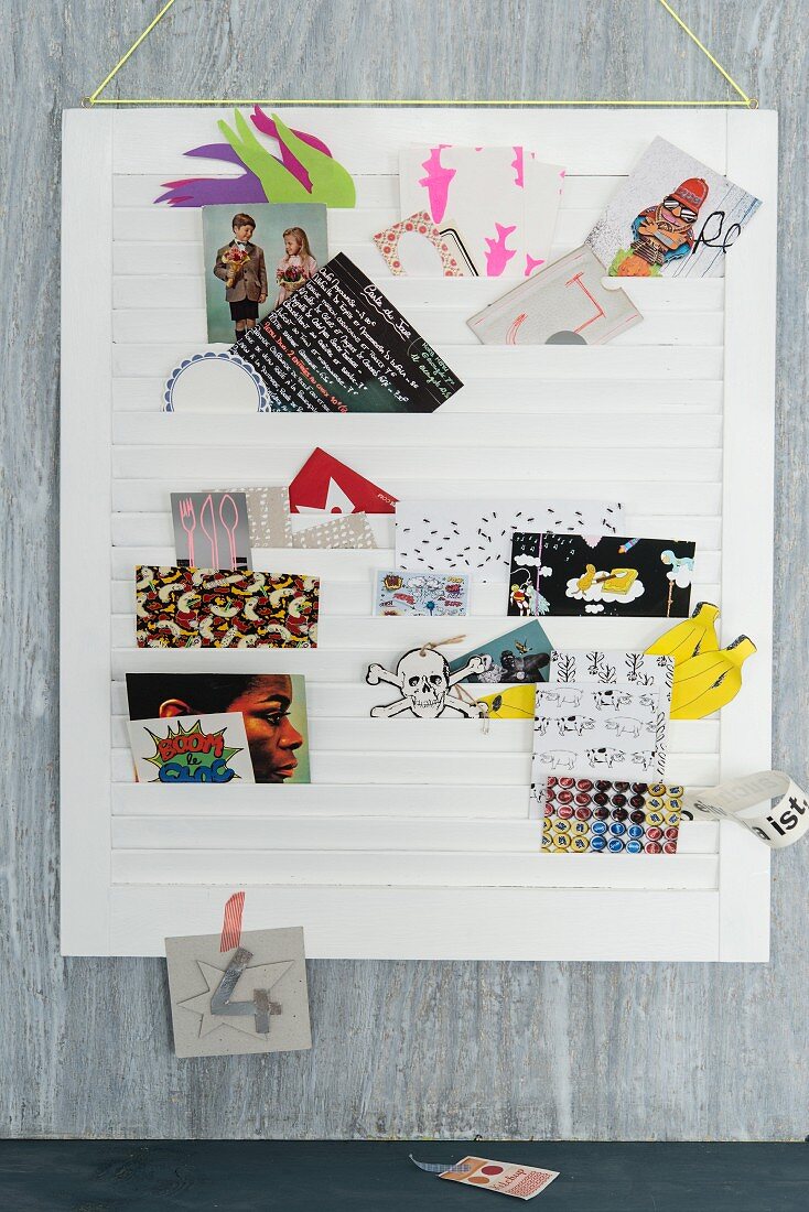 A white slatted frame being used as a pin board