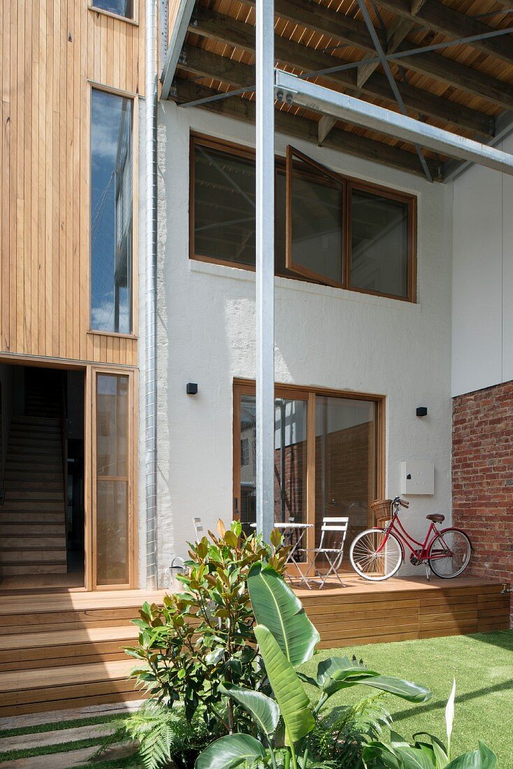 Zeitgenössisches Wohnhaus mit schmaler Terrasse auf Holzpodest