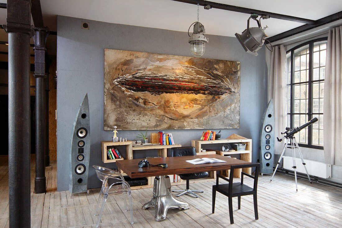 Tischplatte auf extravagantem Metallfuss gegenüber modernes Bild an grauer Wand in Loft-Wohnung