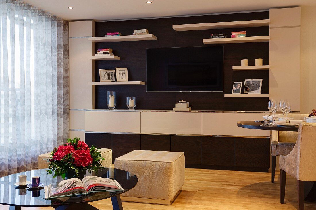 Einbauwand mit Flatscreen in klassisch elegantem Wohnraum mit samtgepolsterten Sitzhockern