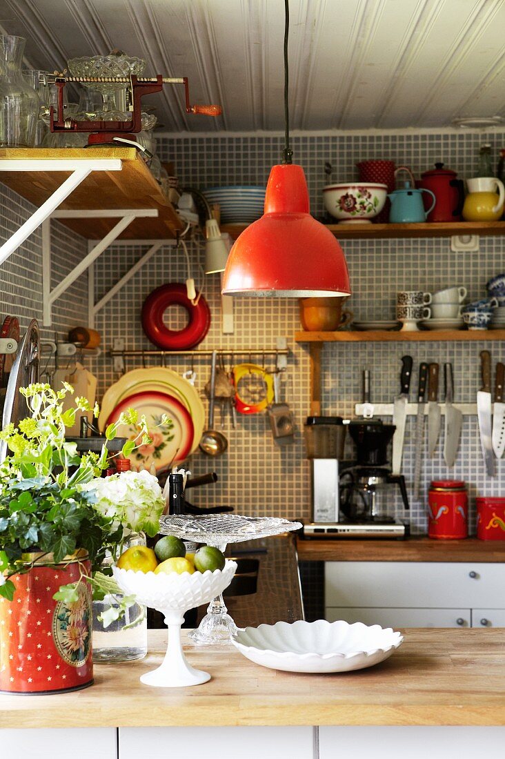 Nostalgische Küchenecke, rote Pendelleuchte über Theke und Küchenutensilien an Wand aufgehängt