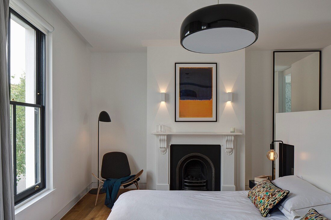 Modernes Schlafzimmer mit Designermöbeln, traditionellem Kamin und reduziertem Flair