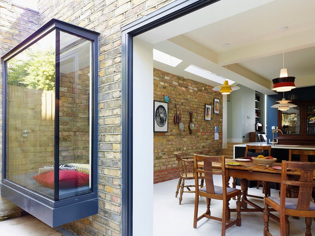 View from terrace into open-plan kitchen with bay window in brick façade and window seat