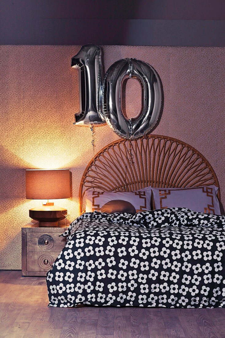 Double bed with a curved headboard made of bamboo, with decorative numbers made of silver balloons