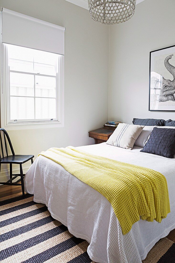 Yellow bedspread on double bed in simple bedroom
