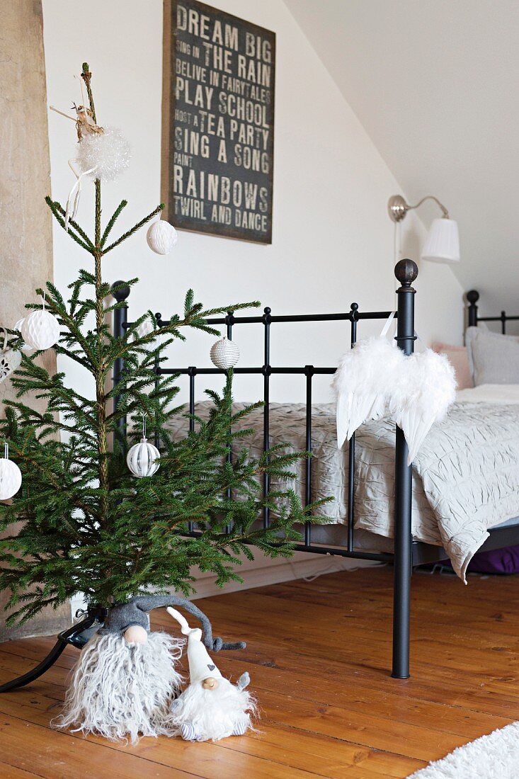 Small Christmas tree and gnomes at foot of metal bed