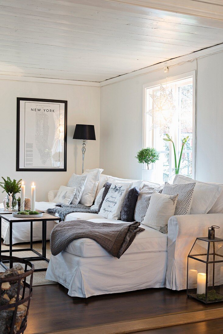 Weißes Sofa mit vielen Kissen im gemütlichen Wohnzimmer